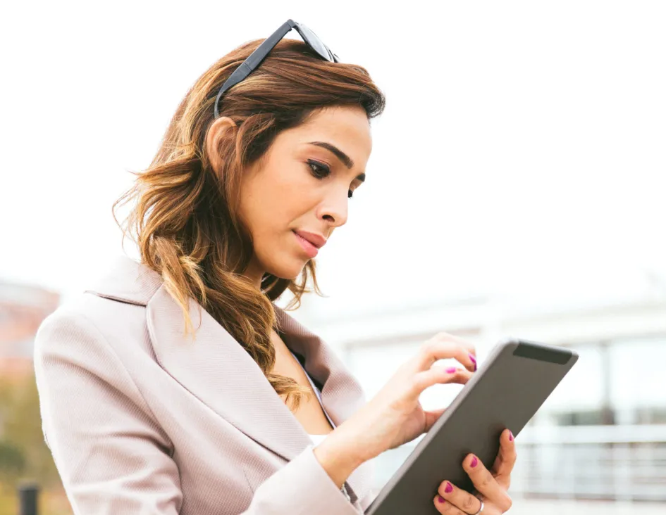 Business woman attempting to zoom on her tablet white walking outside