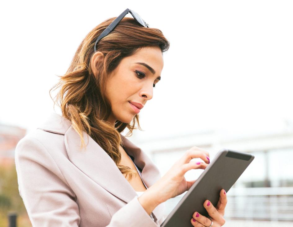Business woman attempting to zoom on her tablet white walking outside