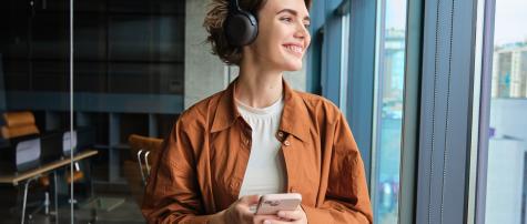 women wearing headphones holding her phone